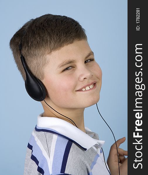 Head shot of a young boy enjoying music on headphones with a blue background. Head shot of a young boy enjoying music on headphones with a blue background.