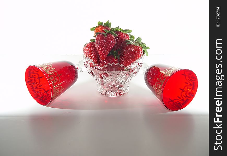 Crystal bowl filled with strawberries including red glasses on a white background. Crystal bowl filled with strawberries including red glasses on a white background.
