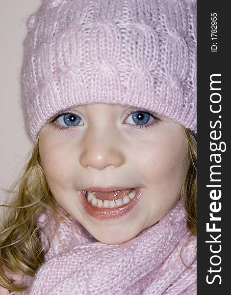 Cute blue eyed girl with matching pink hat and scarf and blond curls laughing in the camera. Cute blue eyed girl with matching pink hat and scarf and blond curls laughing in the camera