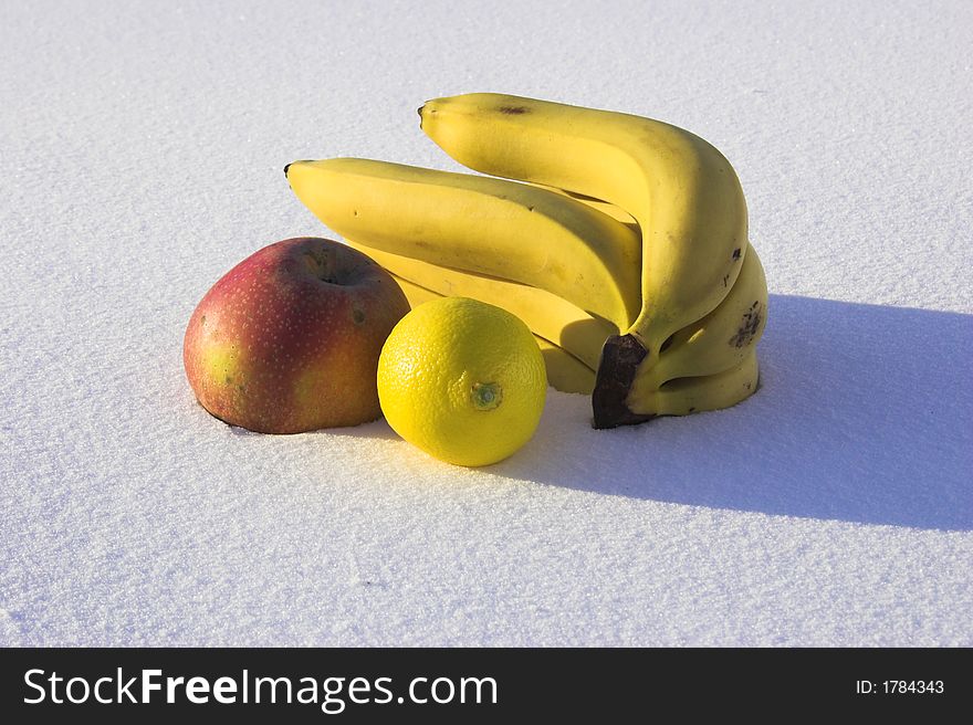 Bananas, mandarin, apple and lemon on the snow with shadow. Bananas, mandarin, apple and lemon on the snow with shadow