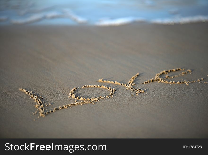 The word love is written by someone on sand. The word love is written by someone on sand