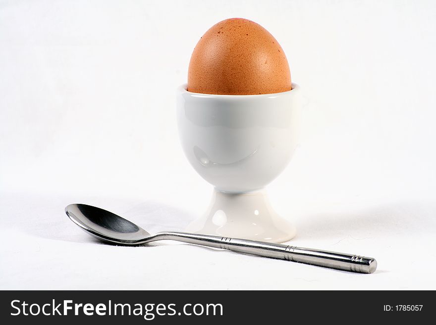 A egg in a egg cup with spoon isolated on white background. A egg in a egg cup with spoon isolated on white background.