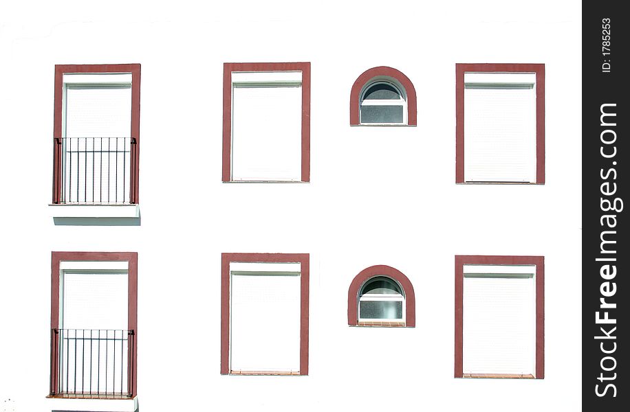 Different shaped windows with red frames all on one wall