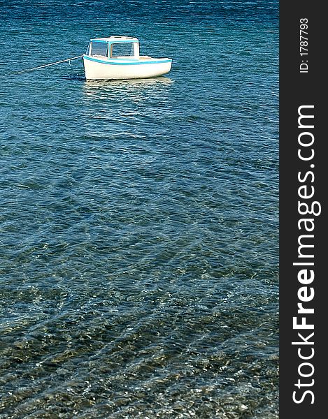 Small boat at anchor in clear blue water. Small boat at anchor in clear blue water