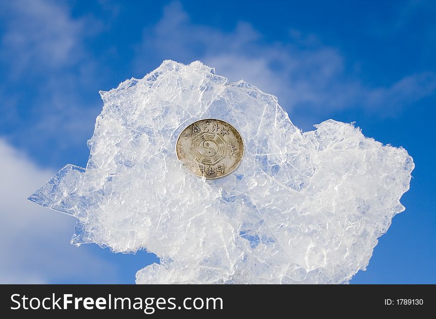Bit of ice wiht coin on blurred sky background. Bit of ice wiht coin on blurred sky background