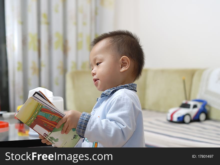 A chinese boy is reading a cartoon book in home. A chinese boy is reading a cartoon book in home.