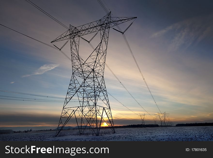 High Volatge Pylon At Sunset In Winter