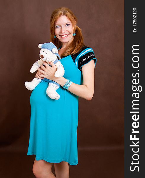 Pregnant young woman with toy in dress