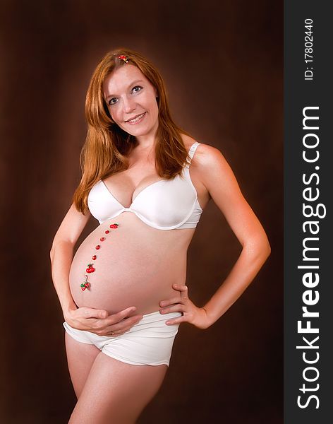 Pregnant young woman in white underclothes with funny motif on abdomen