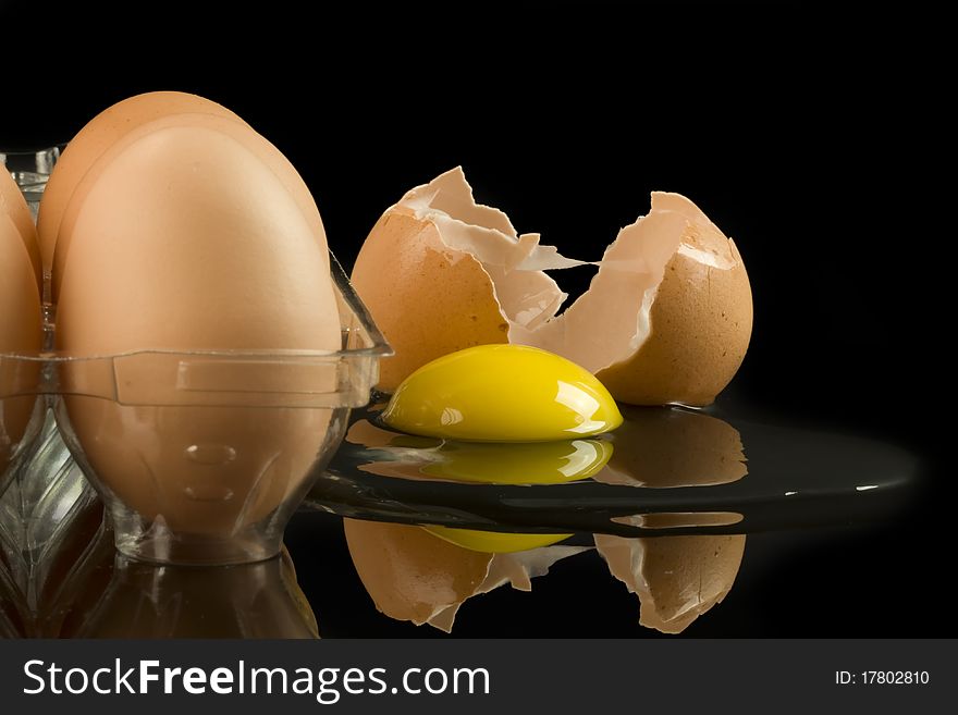 Carton of eggs with one cracked on black background. Carton of eggs with one cracked on black background