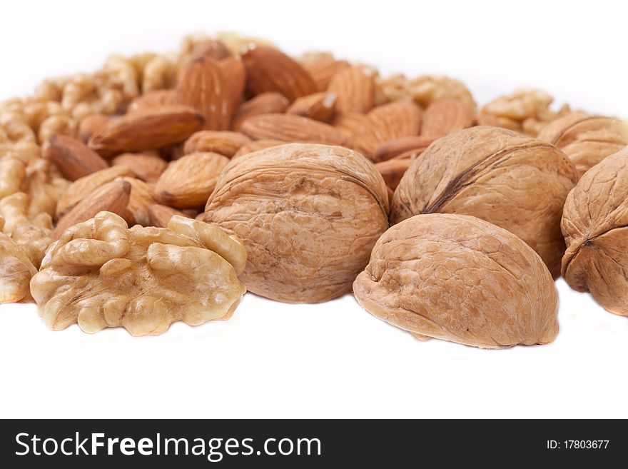 Many the cleared popular nuts lie on a white background. A horizontal shot, focus in the image center. Many the cleared popular nuts lie on a white background. A horizontal shot, focus in the image center