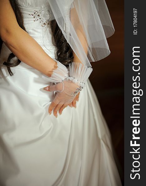 Bride's hands in gloves on wedding dress