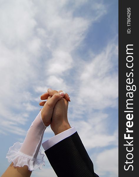 Bride and groom holding hands on sky background