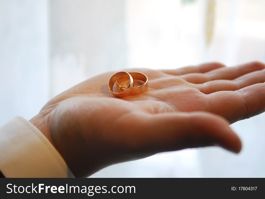 Groom holding two gold wedding rings in palm