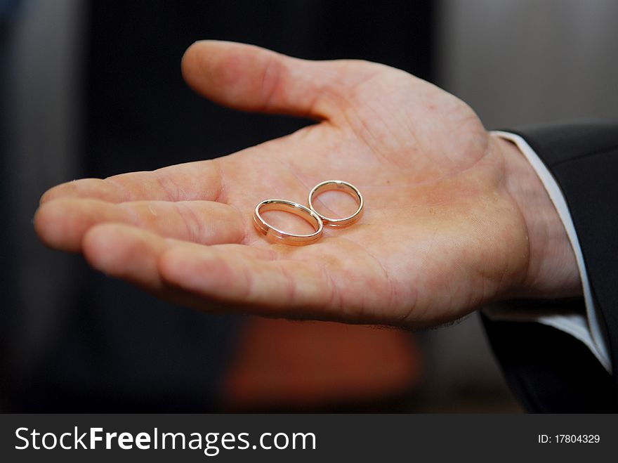 Groom holding two gold wedding rings in palm