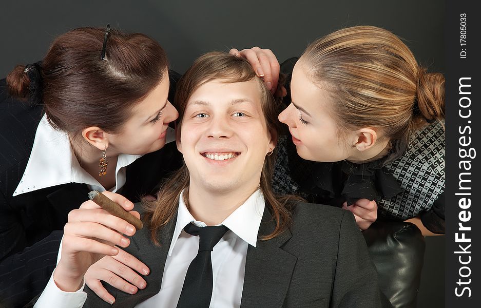 Two secretaries kiss the happy boss