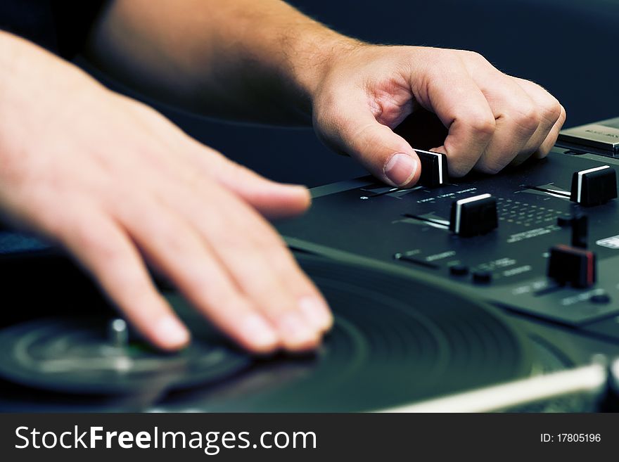 Hands of a disk jockey playing the music on the turntable and top-class mixing controller. Hands of a disk jockey playing the music on the turntable and top-class mixing controller