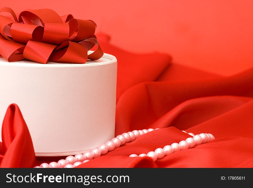 Box with a gift on a red fabric still life