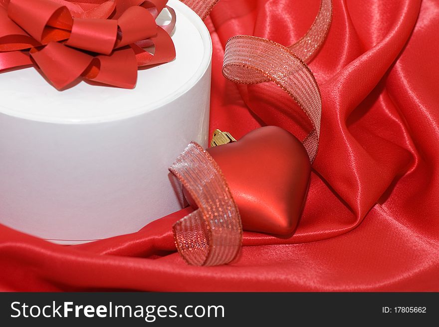 Box with a gift on a red fabric still life