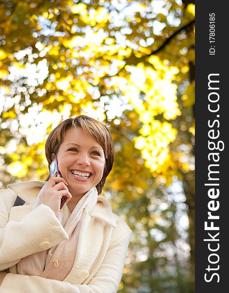 Charming young woman with mobile phone in an autumn park on nature