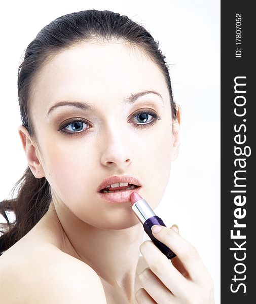 Portrait of beautiful woman applying lipstick using lip concealer brush