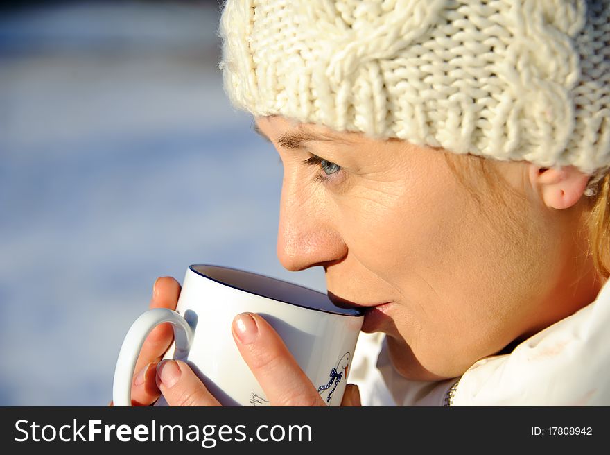 Portrait of adult woman in white, with mug in his hands, bright sunny frosty day