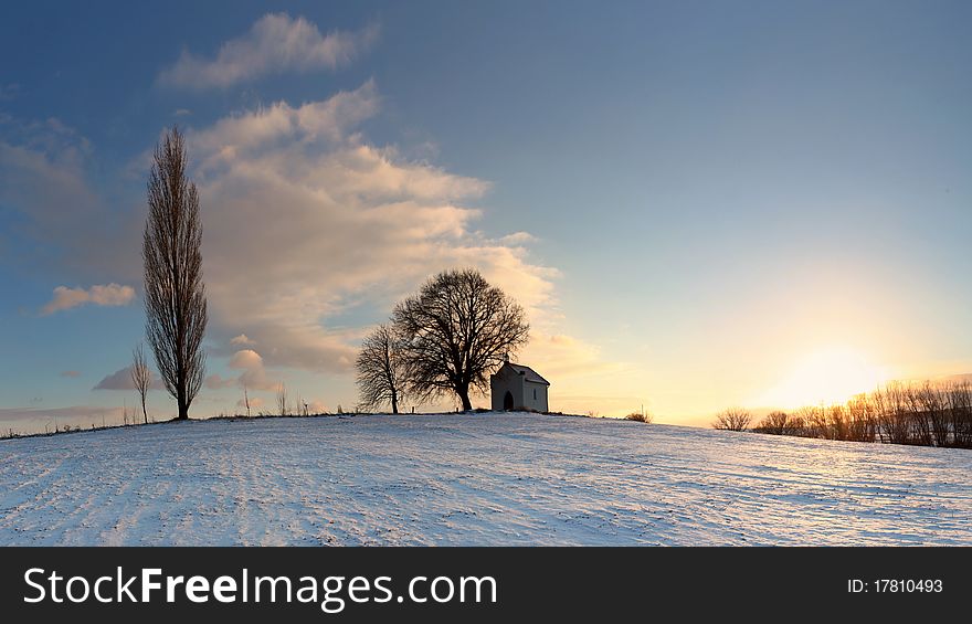 Sunset on frozen field with a chapel