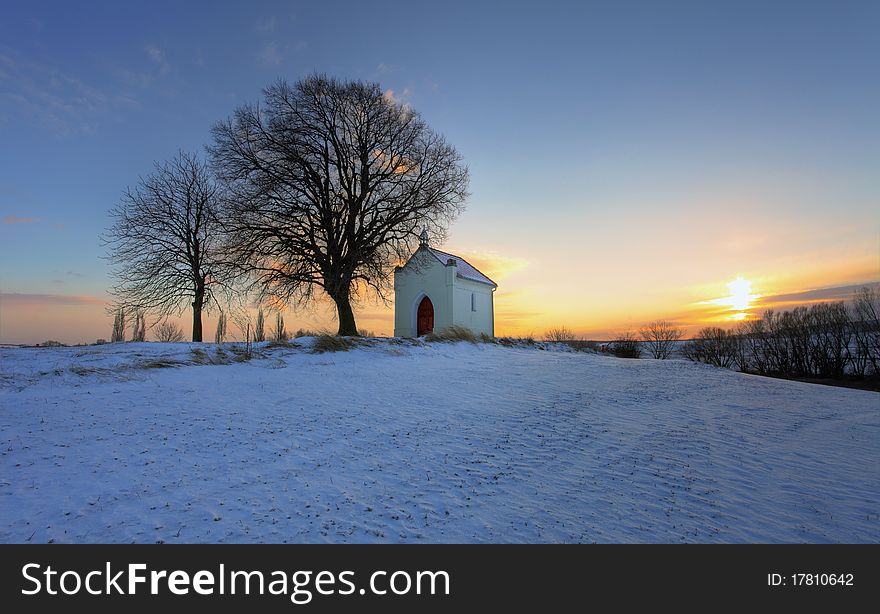 Sunset on frozen field with a chapel