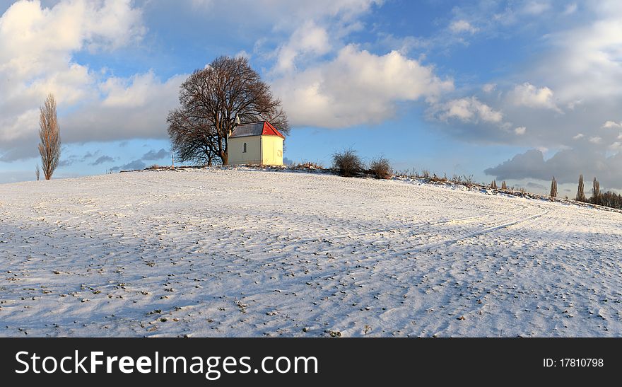 Frozen field with a chapel and clouds - meadow