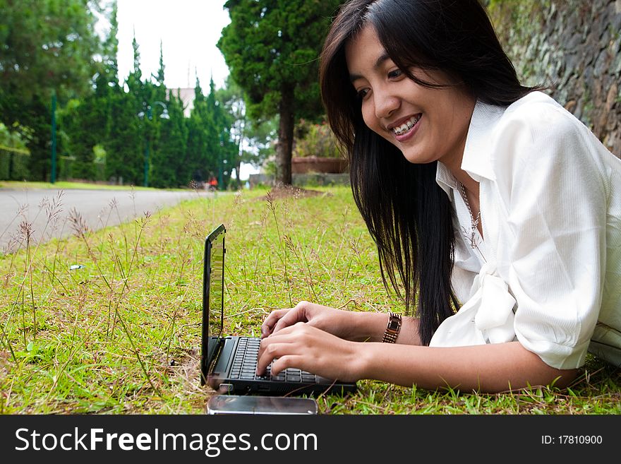 A happy female college student is working in university's park. A happy female college student is working in university's park