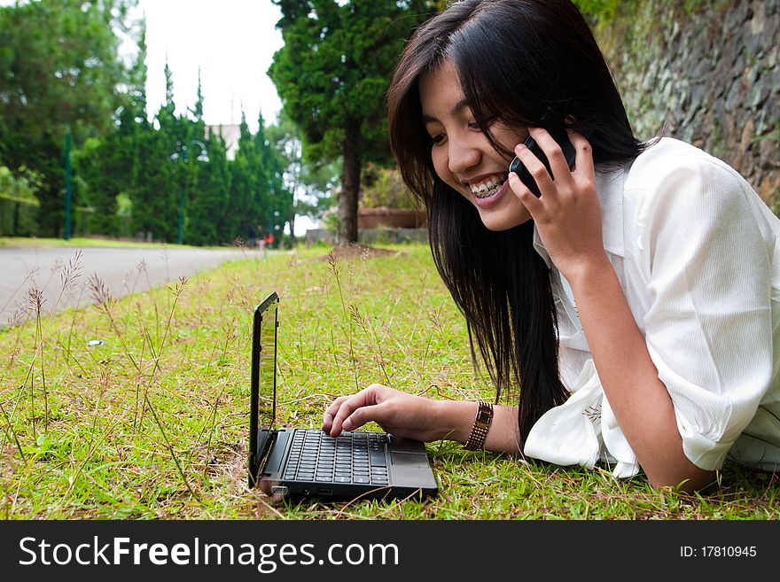 A happy female college student is working in university's park. A happy female college student is working in university's park