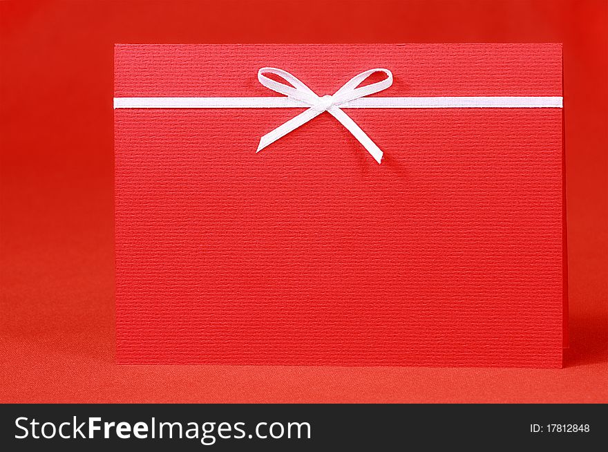 Red invitation card with bow on red silk satin background