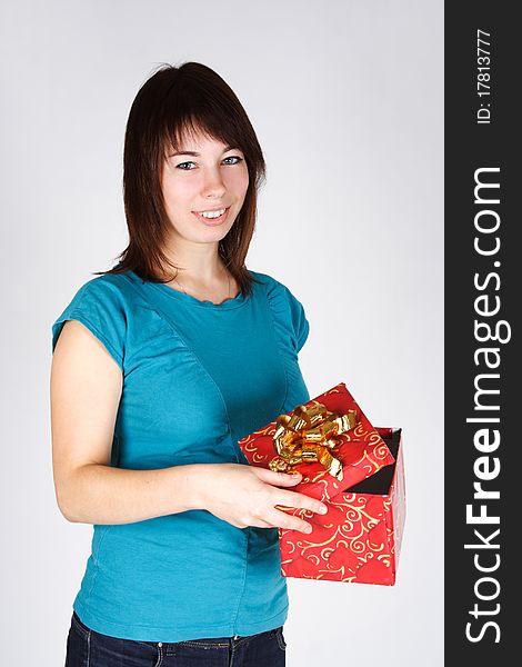 Young brunette girl opening a gift, smiling and looking at camera