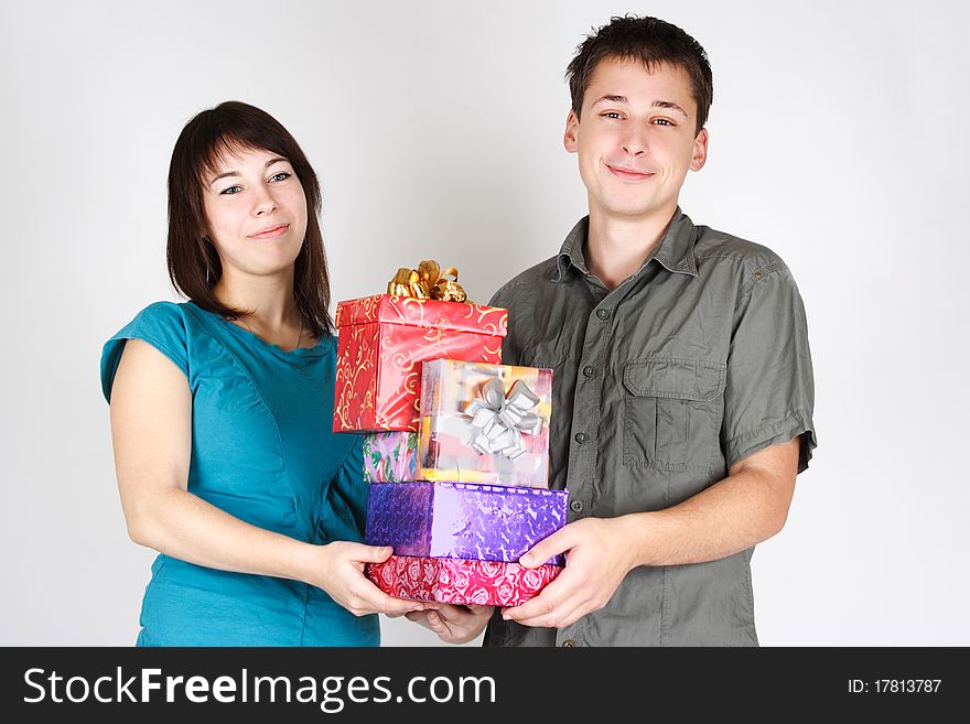 Young happy brunette man and girl holding many gifts and smiling. Young happy brunette man and girl holding many gifts and smiling