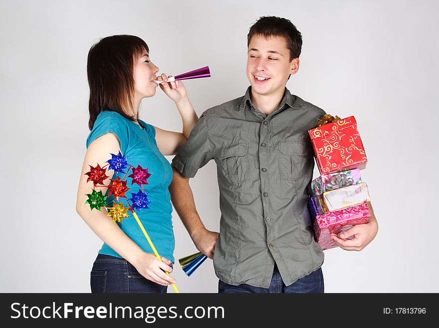 Young happy brunette man and girl holding many gifts and other party items and smiling. Young happy brunette man and girl holding many gifts and other party items and smiling