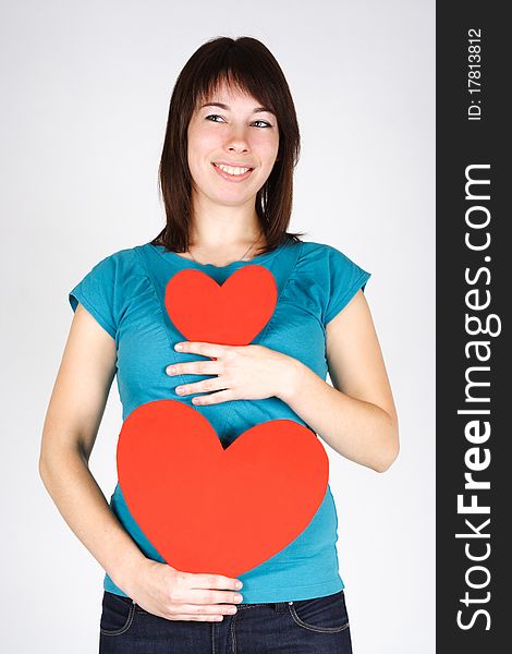 Young beauty girl holding two paper hearts, smiling and looking at side