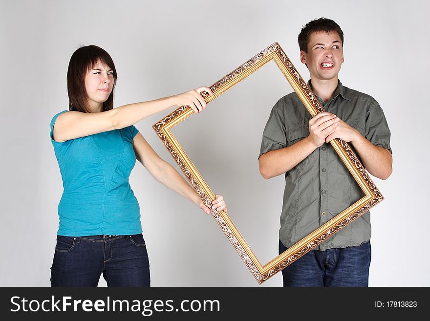 Woman wresting gold decorative frame from man, angry faces. Woman wresting gold decorative frame from man, angry faces