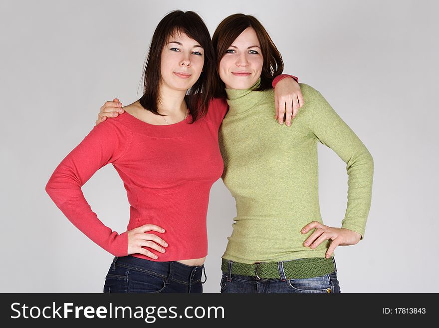 Two young brunette girls in red and green shirts embracing. Two young brunette girls in red and green shirts embracing