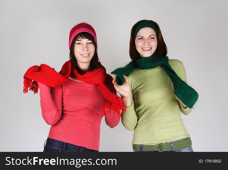 Portrait of two young girls in warm scarfs and hats standing and smiling
