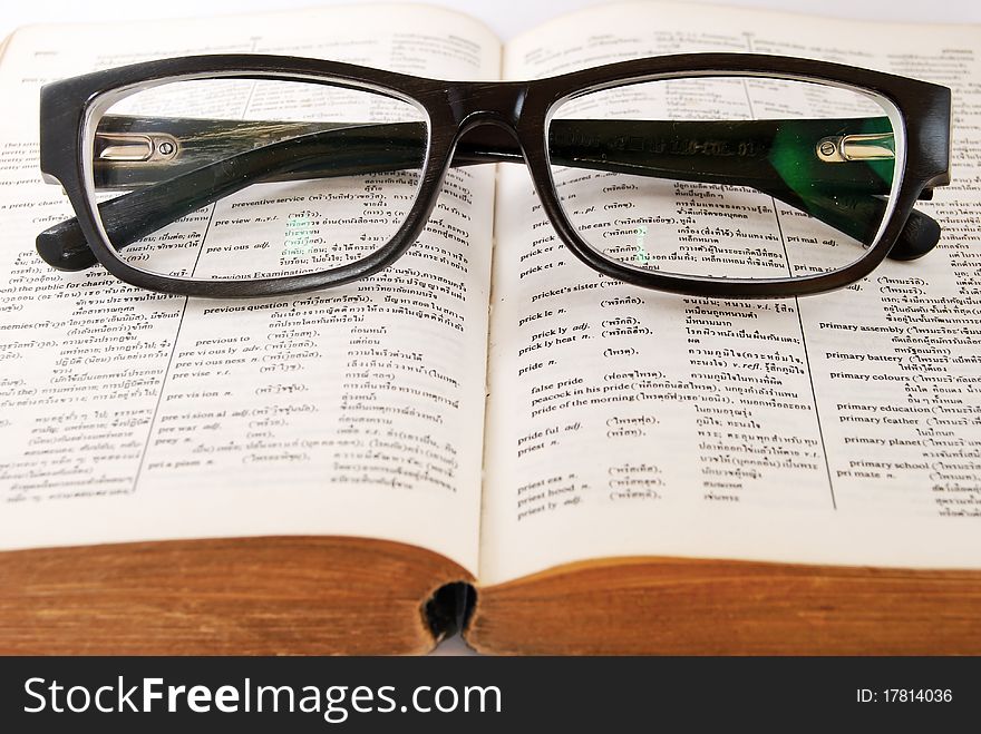 Closeup of old dictionary and black glasses