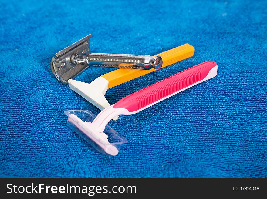 One old and two modern razors are on the blue fabric. One old and two modern razors are on the blue fabric.