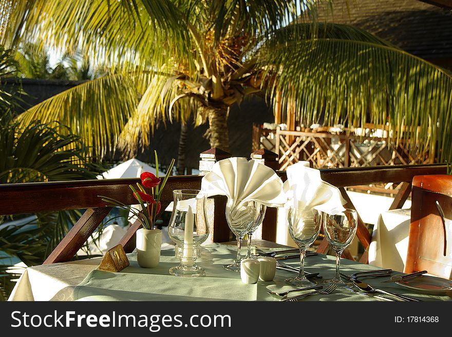 Table dressed up for breakfast in a tropical resort, sun shining and coconut palm in background. Table dressed up for breakfast in a tropical resort, sun shining and coconut palm in background