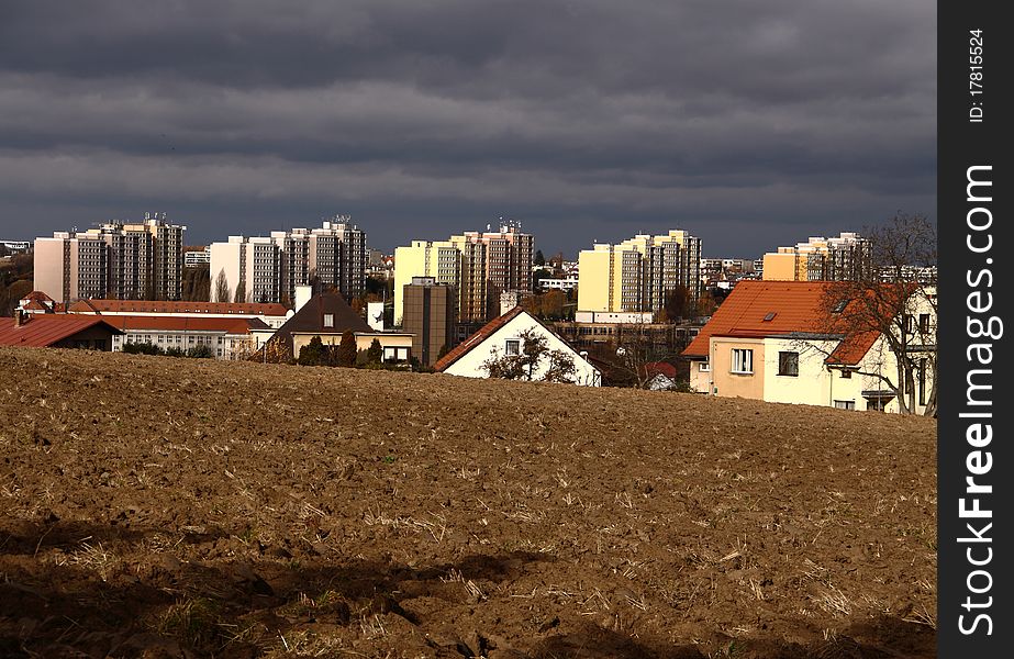 Combination of classical houses and panel houses over the ploughed field