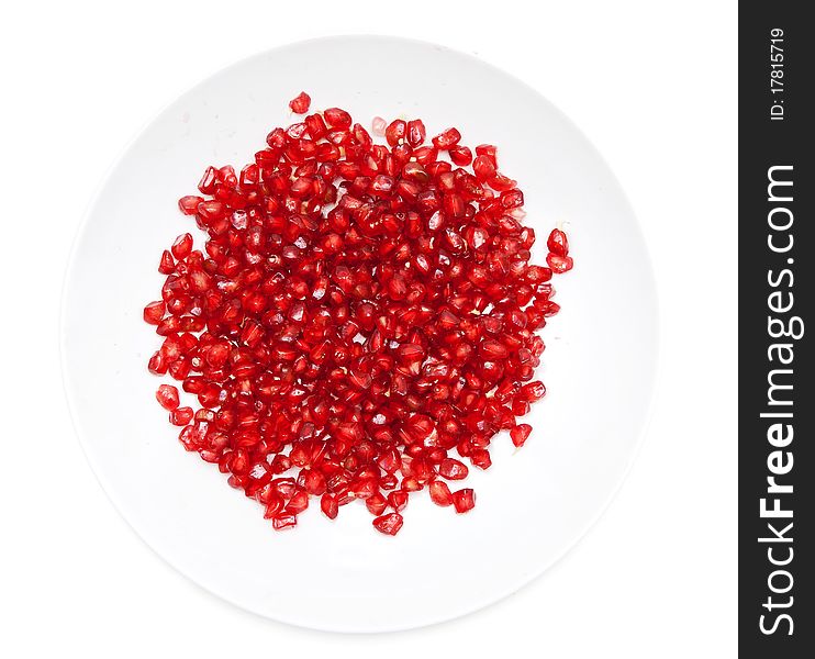 Red pomegranate seeds on a plate on a white background