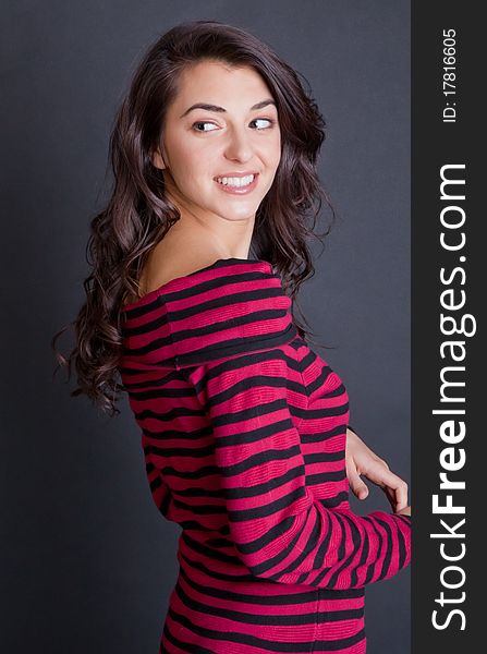 A cute, fun portrait of a beautiful young woman wearing a red and black sweater dress and patterned tights and smiling happily at the viewer. A cute, fun portrait of a beautiful young woman wearing a red and black sweater dress and patterned tights and smiling happily at the viewer.