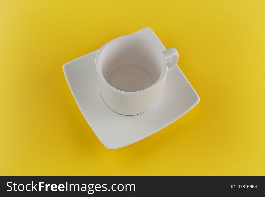 Empty cup with saucer on yellow background. Empty cup with saucer on yellow background.