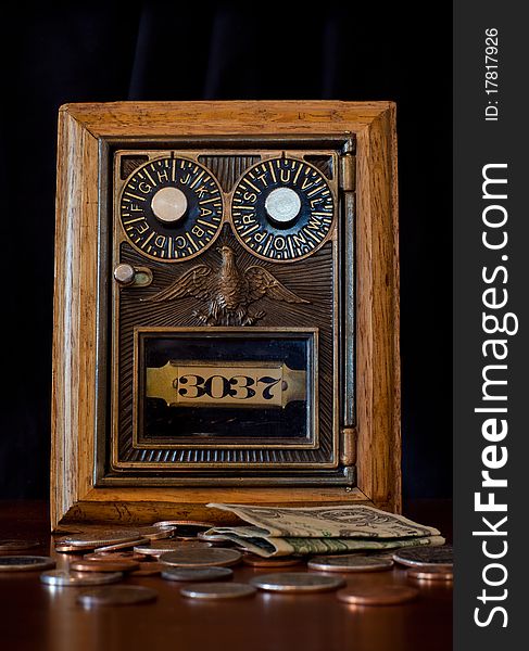 A vintage style combination lock box with money laying loose in the foreground. A vintage style combination lock box with money laying loose in the foreground.