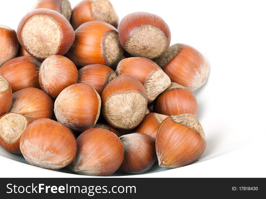 Small group Hazelnut lies on a plate on a white background. A shot horizontal, focus in the shot center