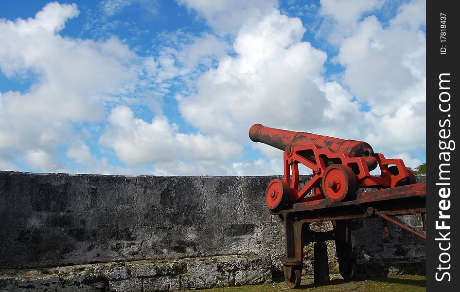 Old war red cannon in a fort directed to the bright blue sky