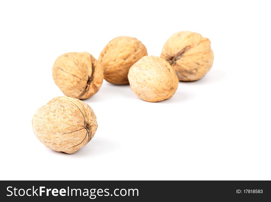Five walnuts lie on a white background. A shot horizontal, focus on a near nut
